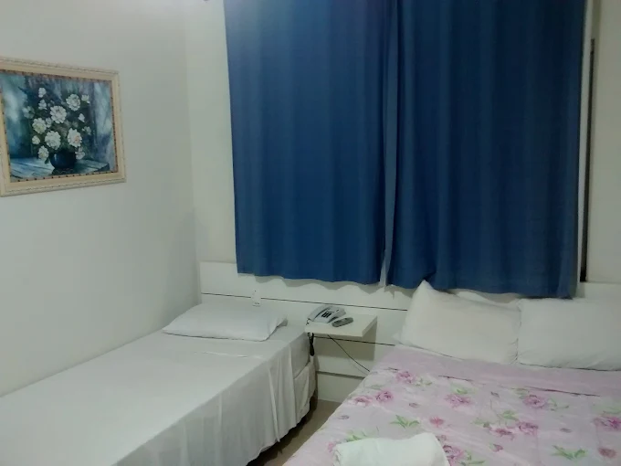 Quarto triplo com cortinas azuis, cama de casal e cama de solteiro
