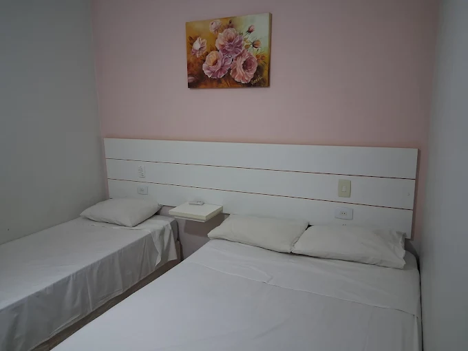 Quarto triplo com parede rosa, cama de casal e cama de solteiro